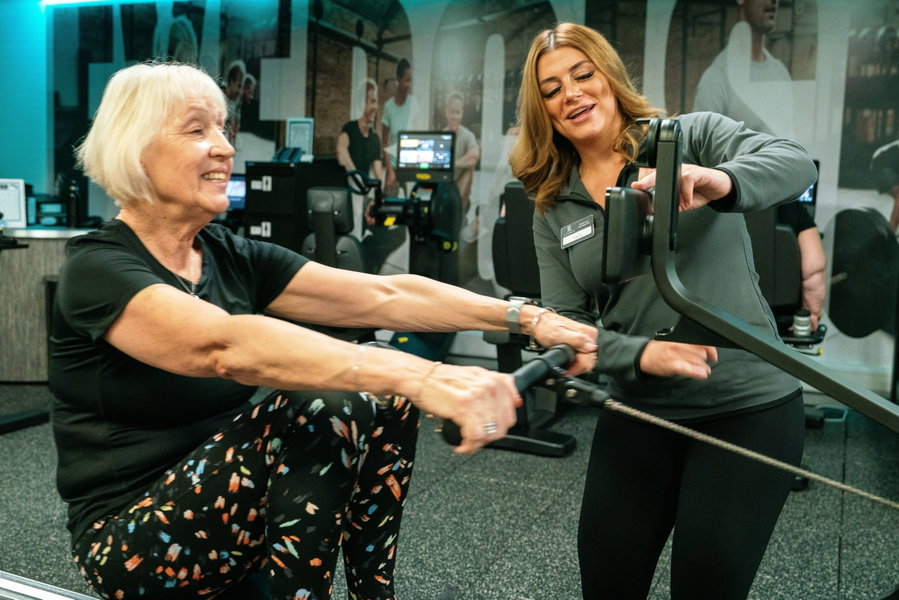 A personal trainer supporting a gym member